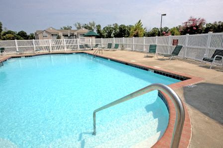 a large swimming pool with chairs and a fence around it